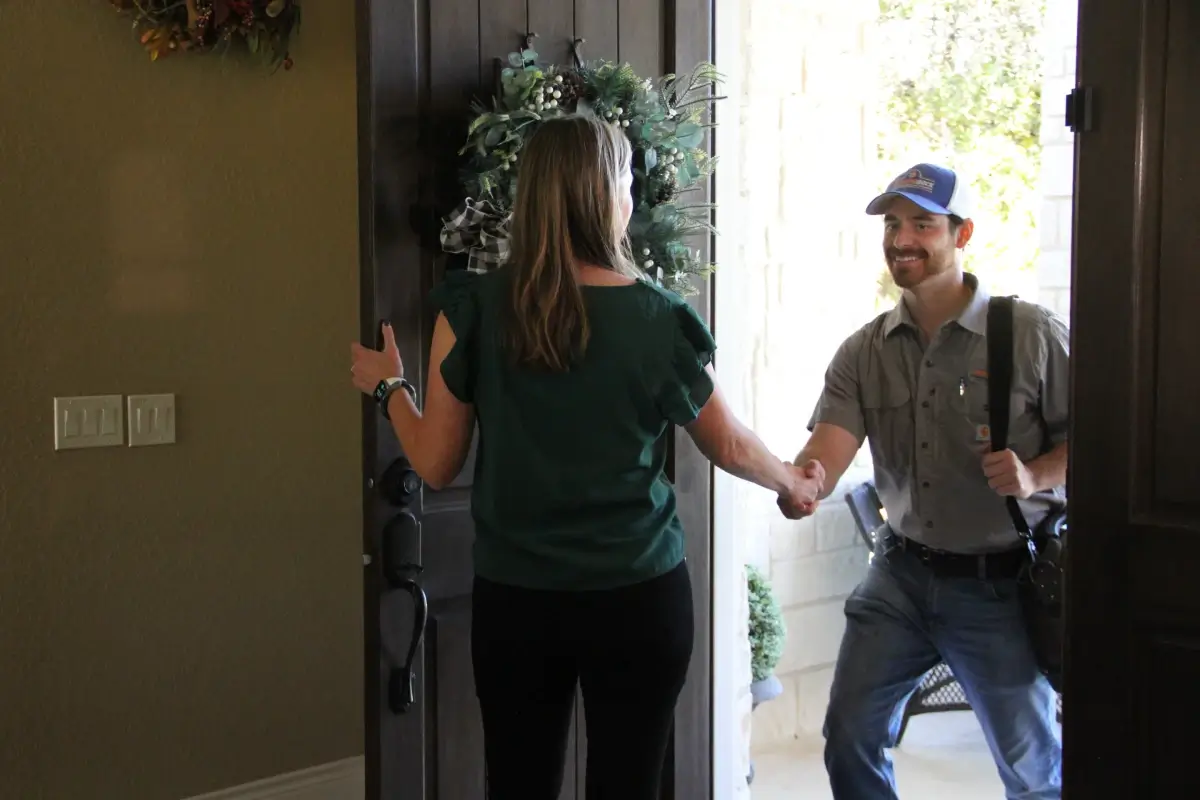Man shaking woman's hand at front door of house
